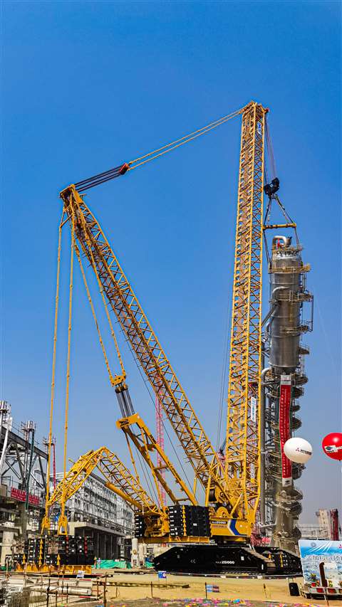 yellow and blue crane lifting a large column