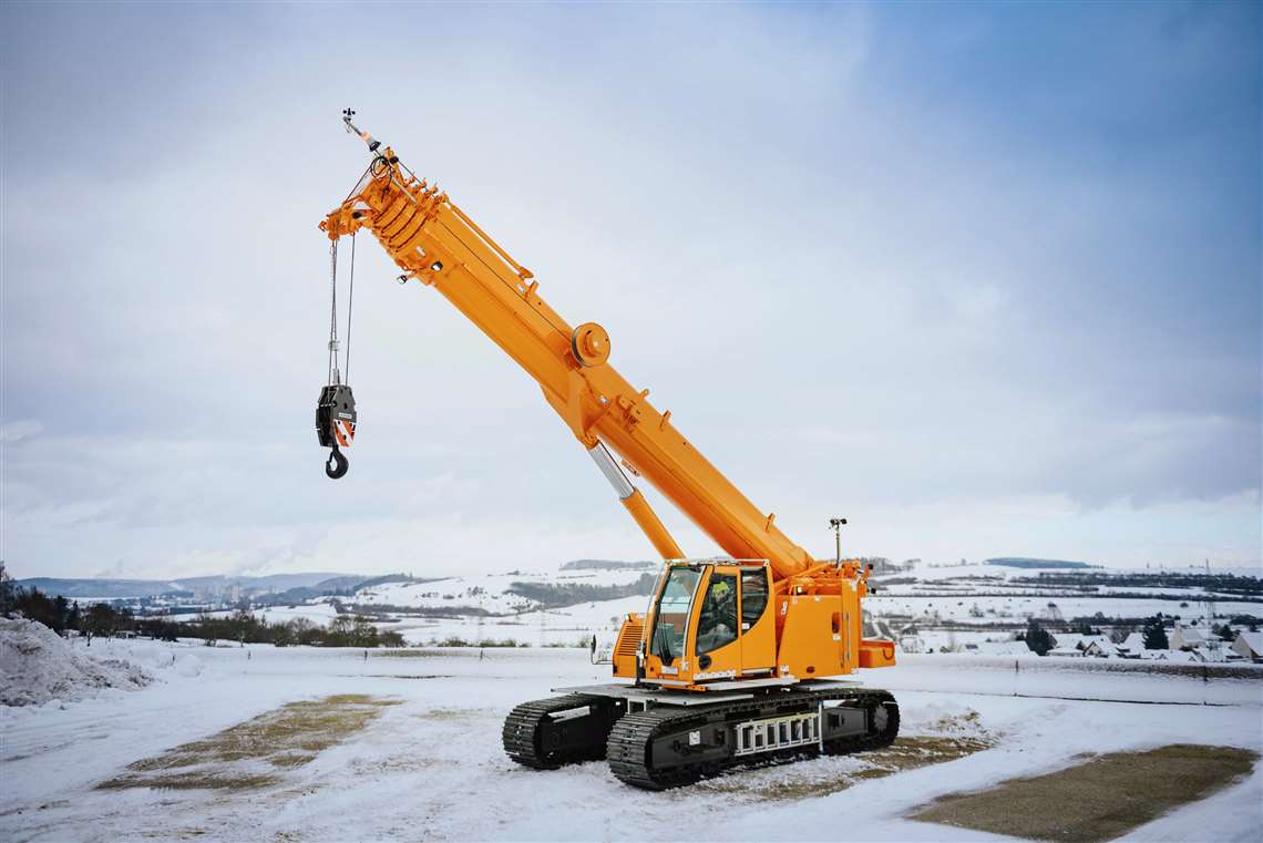 Yellow crawler crane, tele boom up, in the snow