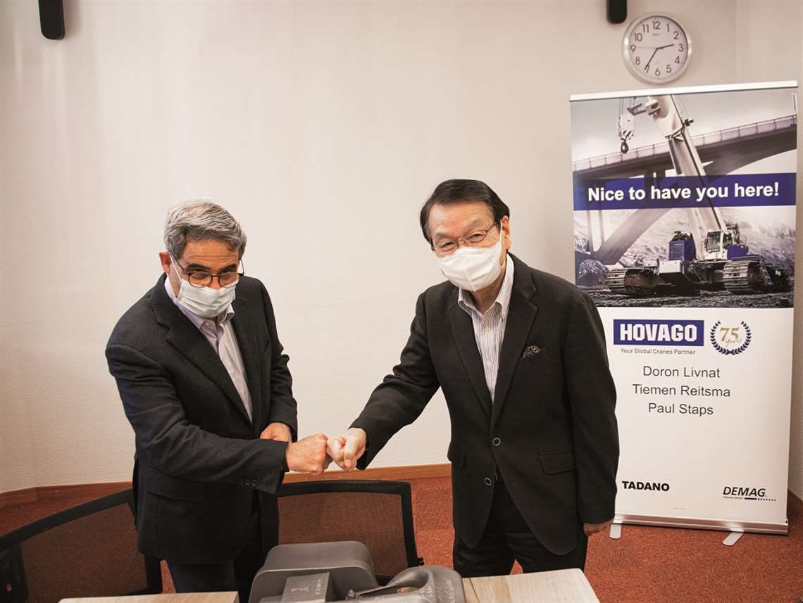 Doron livnat of Hovago shakes hands with Tadashi Suzuki from Tadano, both in facemasks to protect againts corona