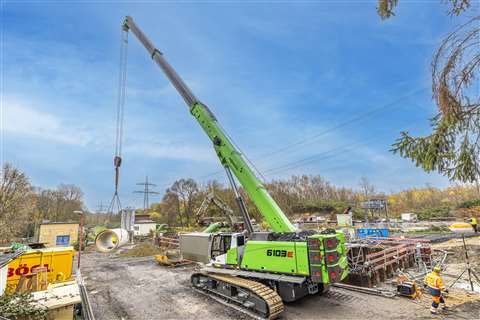 rear three quarter view of a green tele boom crawler on a busy site