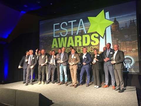 A group of men and women on stage in front of ESTA Awards banner backdrop