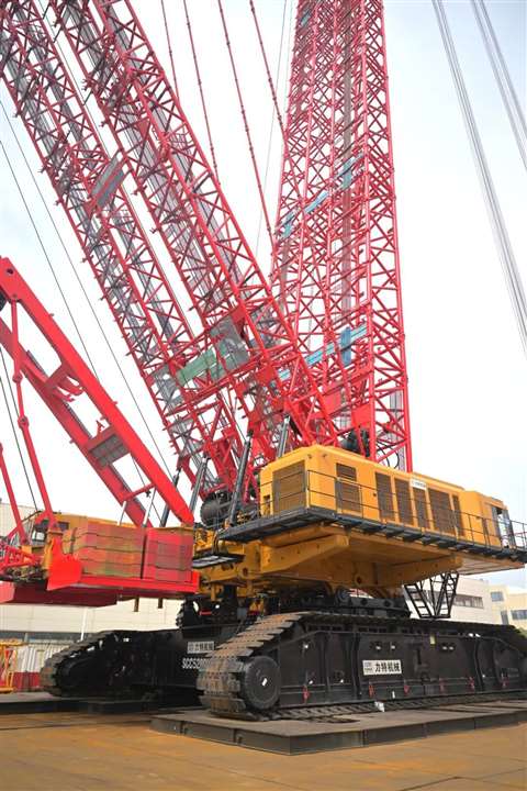 rear three quarter view of red and yellow crawler crane